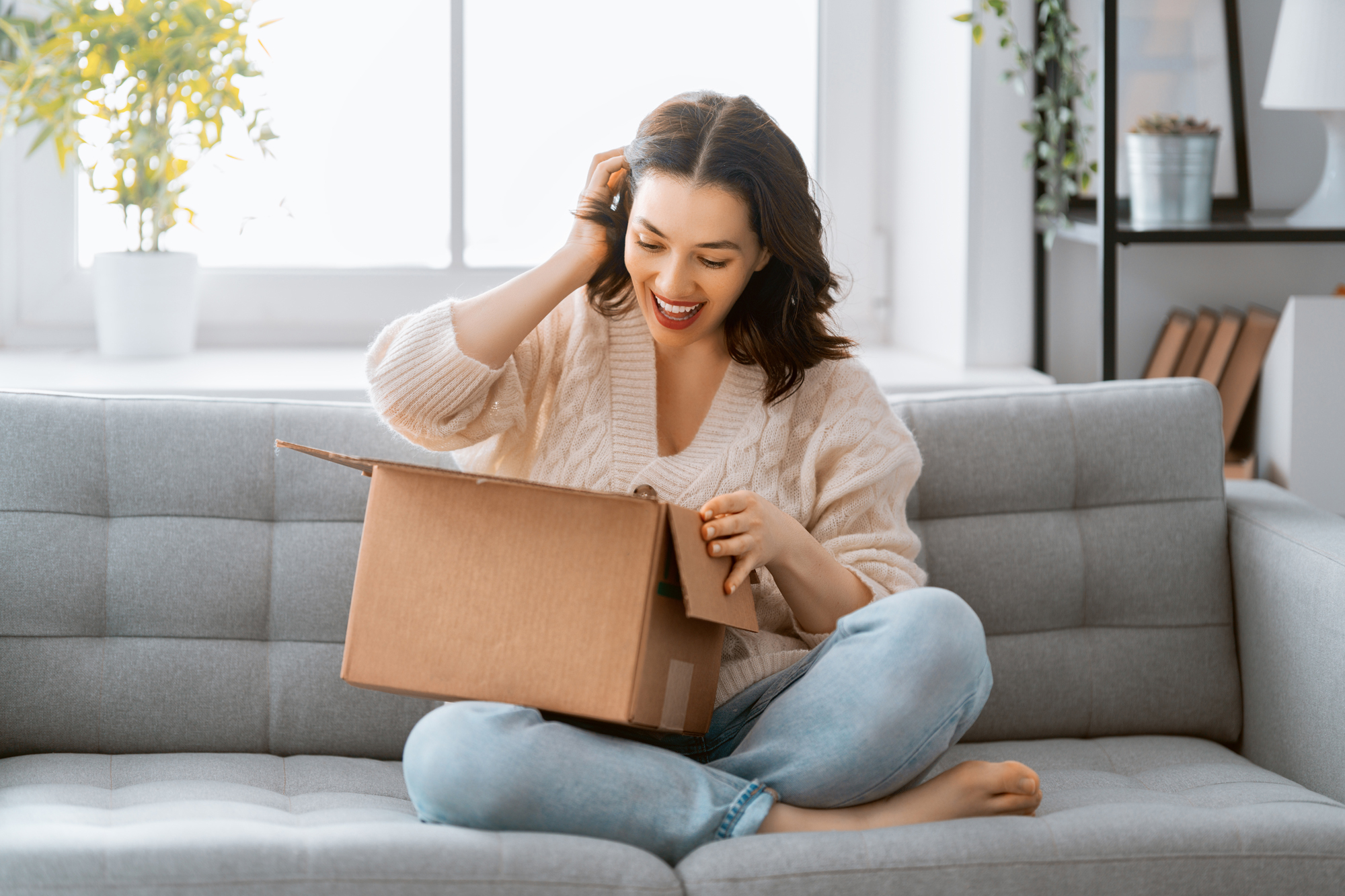 Woman Opening Parcel on Sofa